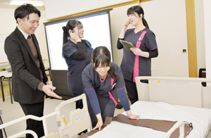 香田さん(写真左)の説明でIT機器を体験する学生たち == 株式会社伝書鳩|経済の伝書鳩|北見・網走・オホーツクのフリーペーパー ==